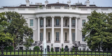 A classic view of the White House in Washington DC with lush greenery and fountains.