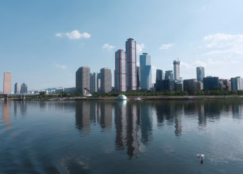 A stunning Seoul skyline reflecting in the river under a clear blue sky.