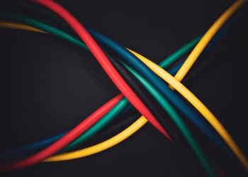 Multi-colored cables intertwined against a dark background, showing technology connections.