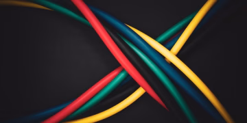 Multi-colored cables intertwined against a dark background, showing technology connections.