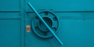 Close-up of a teal metal door with industrial gear mechanism, showcasing intricate machinery details.