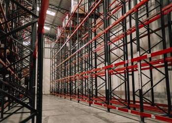 Spacious warehouse interior featuring empty metal racks and high ceiling.