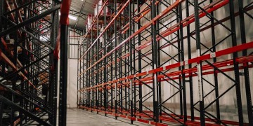 Spacious warehouse interior featuring empty metal racks and high ceiling.