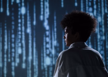 Side view of a teenager observing futuristic digital code on a screen.