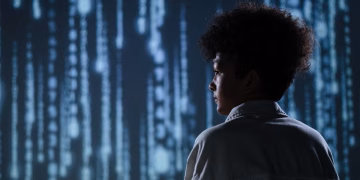 Side view of a teenager observing futuristic digital code on a screen.