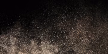 A mesmerizing display of dust particles floating against a dark backdrop, creating a textured effect.