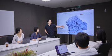 SK텔레콤과 SK바이오팜 연구진이 회의실 화면의 ROR1 결합 구조를 보며 논의하는 모습