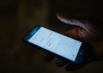 어두운 곳에서 스마트폰 메시지 대화창을 보는 손