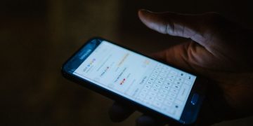 어두운 곳에서 스마트폰 메시지 대화창을 보는 손