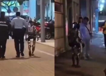 야간 보도에서 현장 관계자 두 명과 휴머노이드 로봇이 함께 걷는 장면