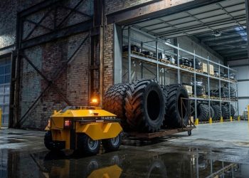 야외 산업 시설에서 대형 타이어 카트를 견인하는 Ati Robotics Sherpa 로봇
