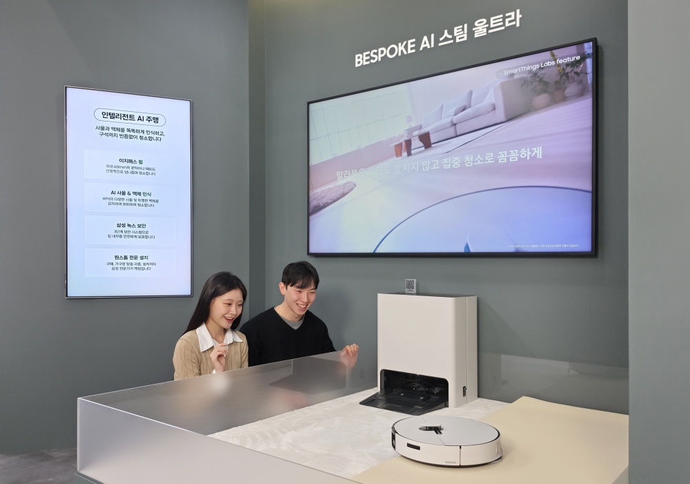 삼성전자 모델들이 KES 2026 삼성전자관에서 로봇청소기를 살펴보고 있다