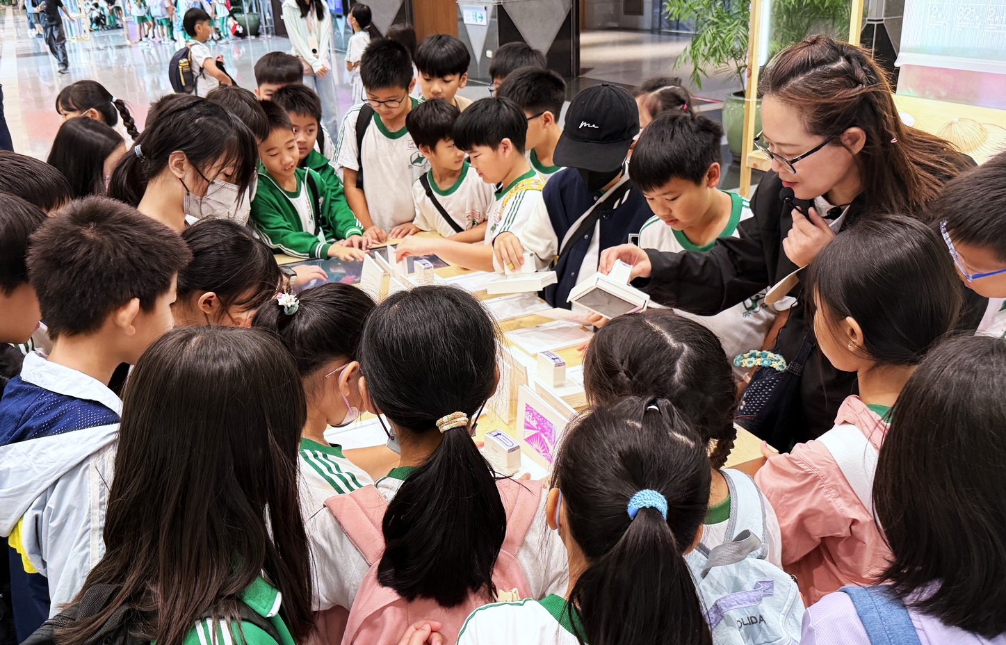 신베이시청 교육 성과전에서 학생들이 안내를 들으며 전시물을 살펴보고 있다. 新北市政府教育局 2026「國慶連假來逛展!新北教育成果展解任務換限量好禮 探索幸福光島、收藏AI回信 完成指定任務有機會抽中平板」보도 사진. 정부자료개방허가조항 제1판에 따라 공개된 자료이며 해당 조건을 준수하여 이용할 수 있다. 허가 조항: https://data.gov.tw/license